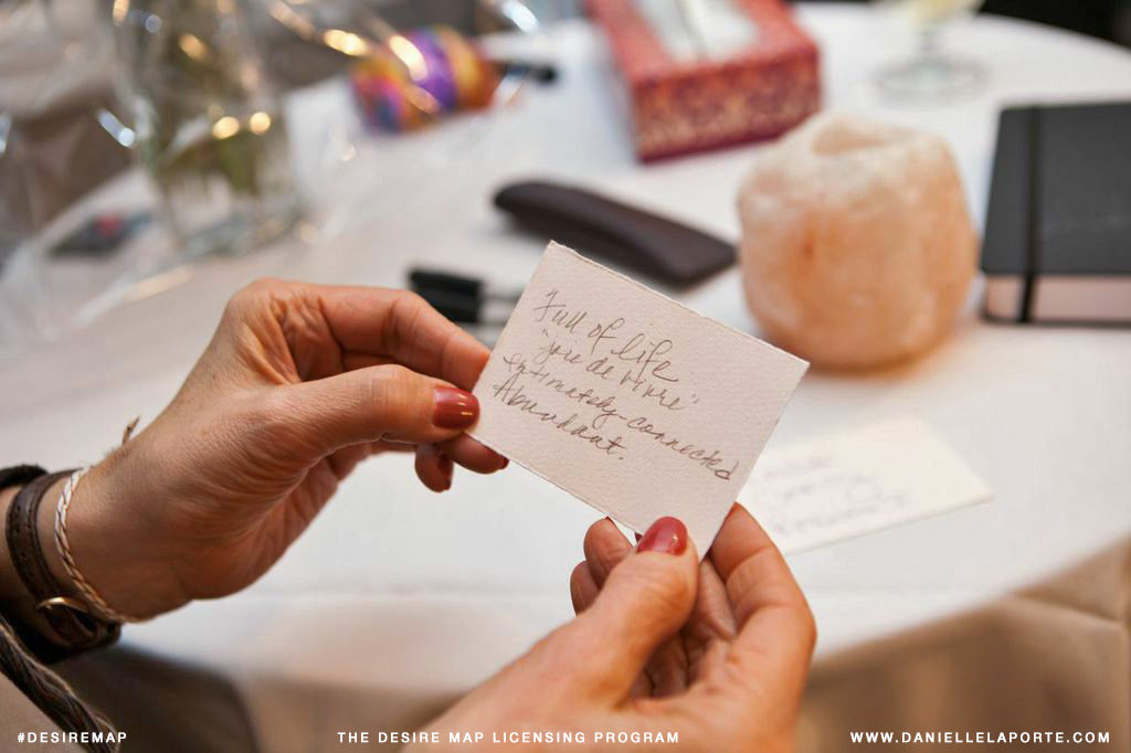 Woman holding a card describing her Core Desired Feelings while attending a Desire Map workshop